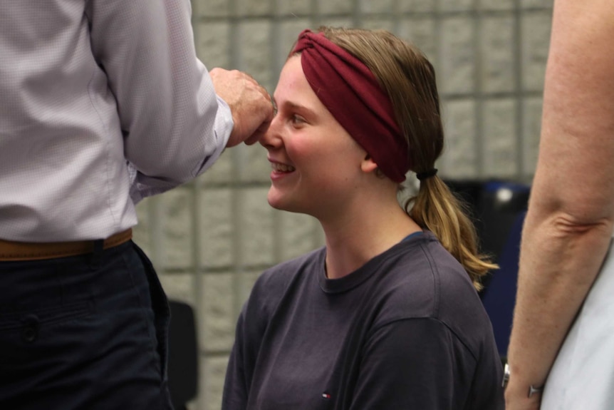 A small camera is placed into the nasal cavity of a student, who is sitting on a chair.