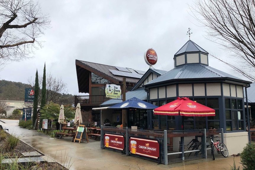 The exterior of the Duck Inn pub, with chairs and umbrellas outside on a cloudy day.