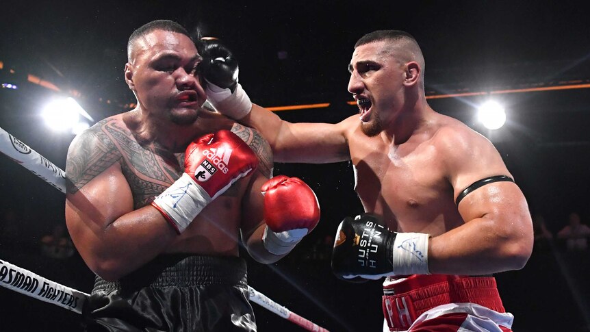 Faiga Opelu's (left) face is contorted as Justis Huni (right) lands a right-hand punch.