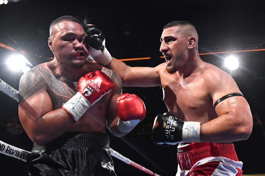 Faiga Opelu's (left) face is contorted as Justis Huni (right) lands a right-hand punch.