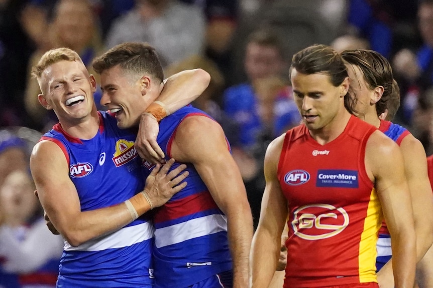 Two Western Bulldogs AFL players embrace as they celebrate a goal against Gold Coast.