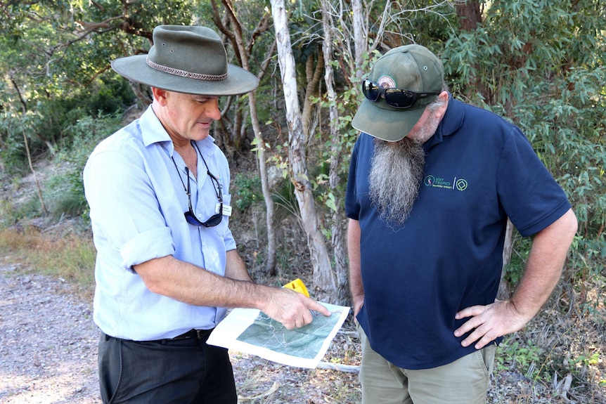 Two men stand together looking at a map