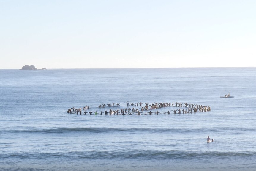 Surfers form a circle in ocean