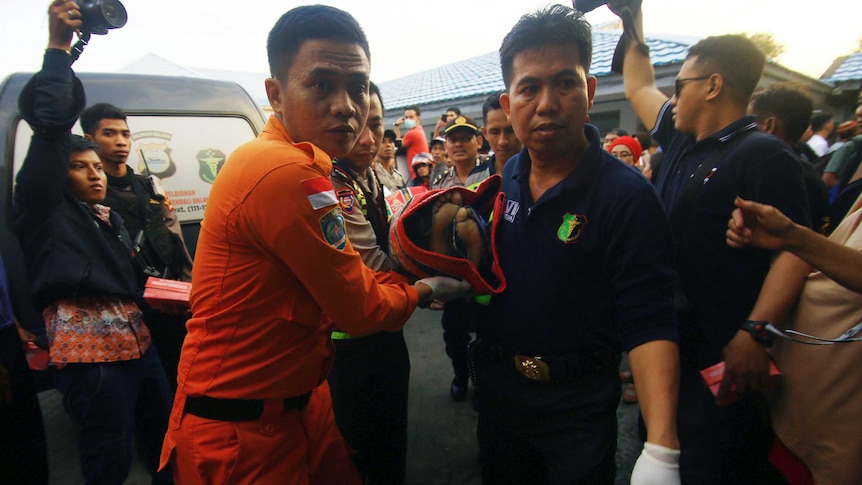 Workers carry a victim through crowd