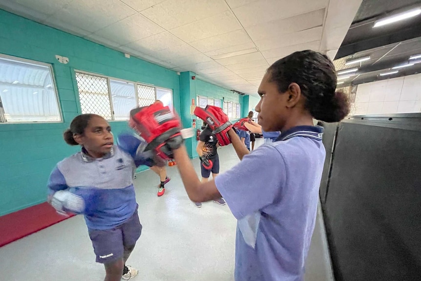 Two high school students training with boxing pads