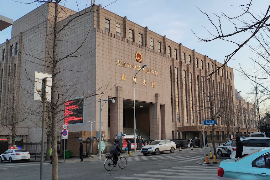 A man on a bike rides past the Intermediate People's Court of Dalian.