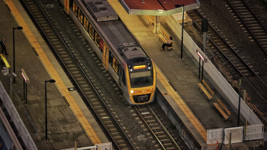 Looking down at train and commuters wait at platform at South Brisbane railway station.