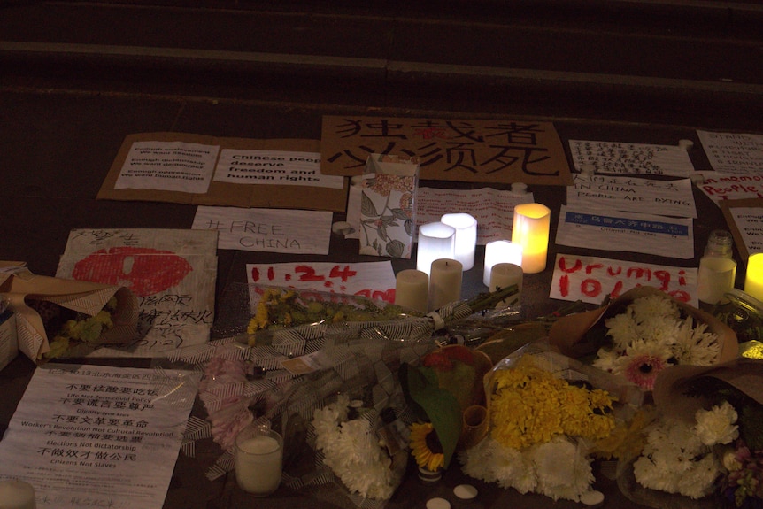 A vigil with candles and signs in Chinese. 