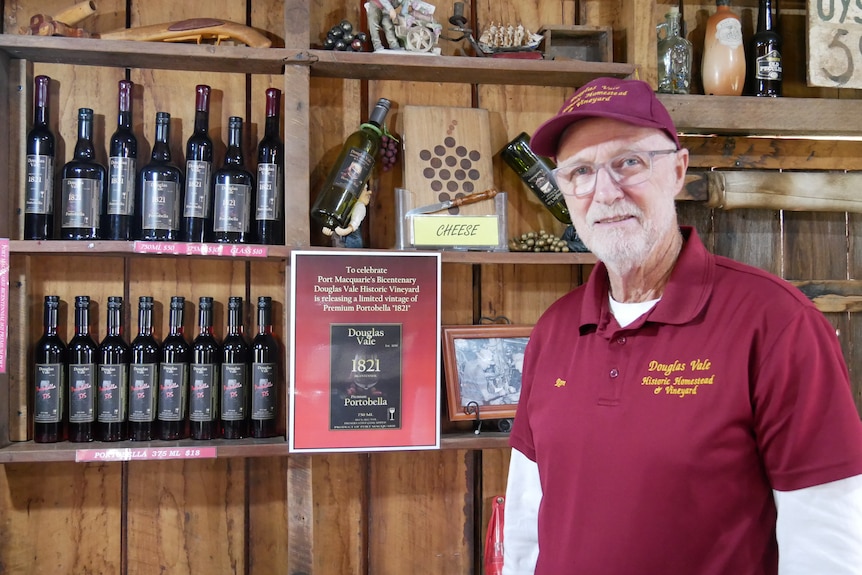 Ron Henkin stands in front of wooden shelf with a variety of wines on it. 