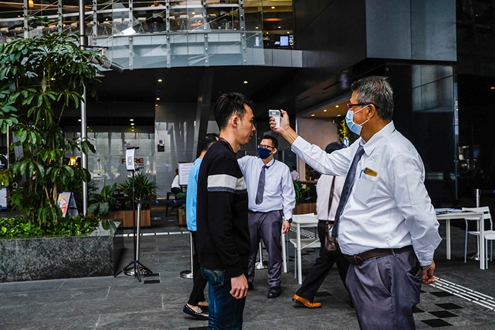 A man is temperature checked outside Asia Square Tower in Singapore.