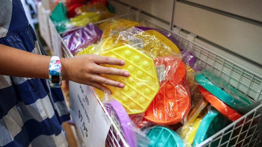 a school child reaching into a basket of multi coloured plastic discs with bubbles