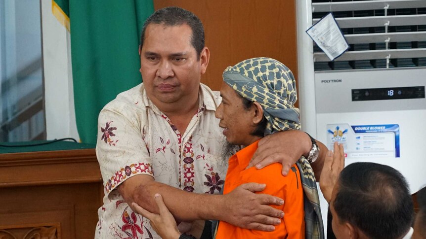 Denny Mahieu and Aman Abdurrahman hug.