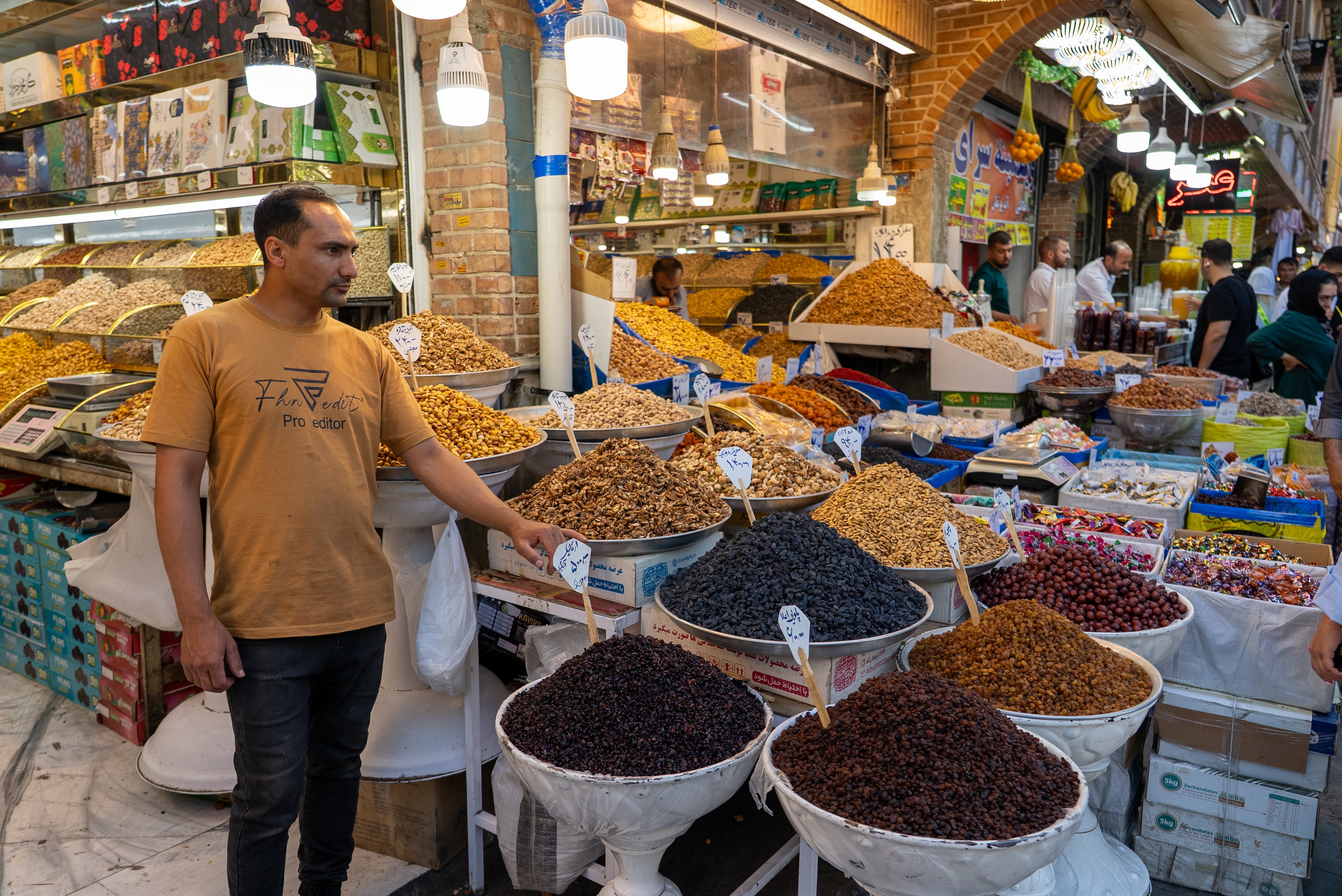 A merchant standing at a market stall with several different spices on display.