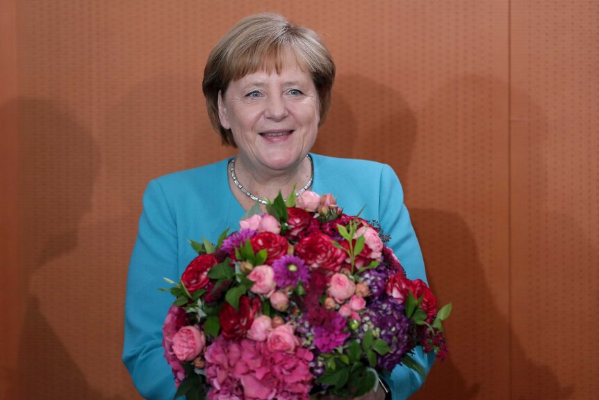 German Chancellor Angela Merkel holds a bunch of flowers that she received as a birthday present.