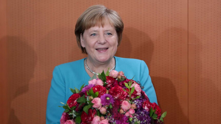 German Chancellor Angela Merkel holds a bunch of flowers that she received as a birthday present.