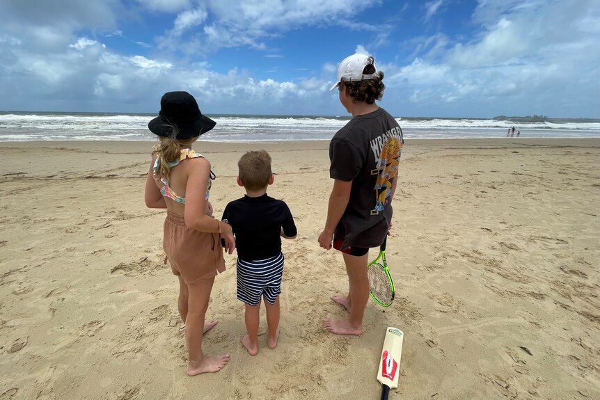 Lenny, Annabelle and Henry Edwards (L to R) look out at rough surf conditions at Maroochydore on Queensland's Sunshine Coast.