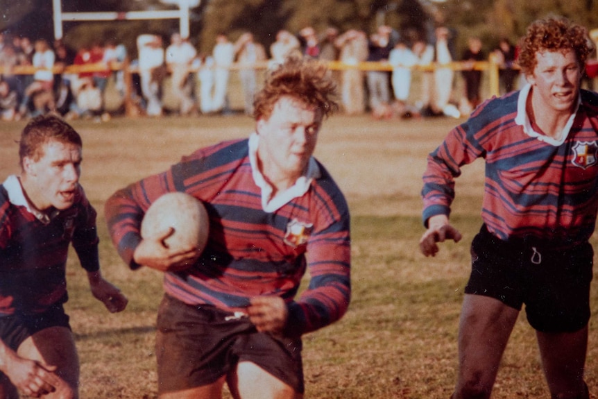 A schoolboy runs with a ball while playing rugby union.