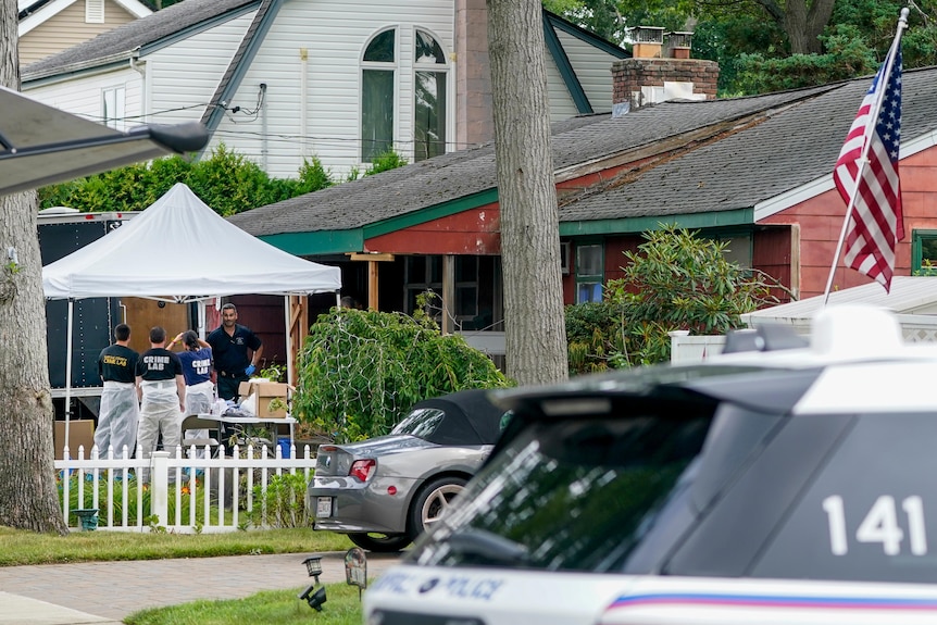 Police officers under a tent outside a suburban home