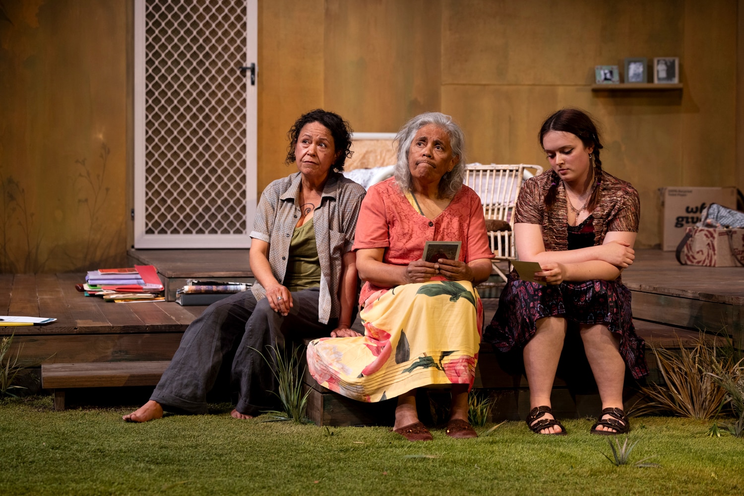 A grandmother and granddaughter who look Aboriginal sit on a porch.