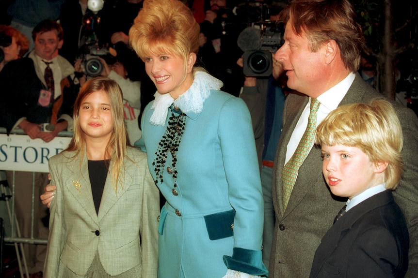 From left, a girl in a green suit, woman in blue suit, older man in green suit and boy in dark suit. All are smiling