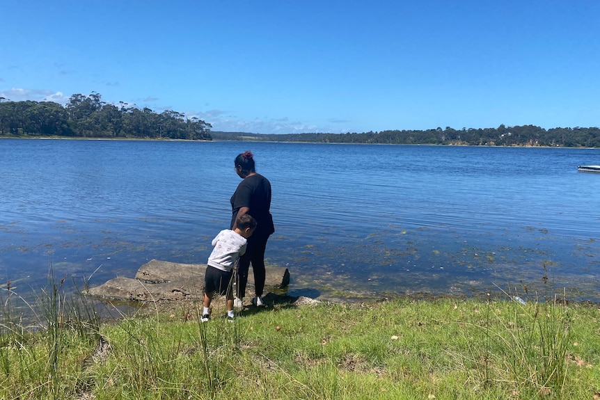 A young woman and a young boy look at a lake.