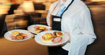 A hospitality worker carrying plates of food