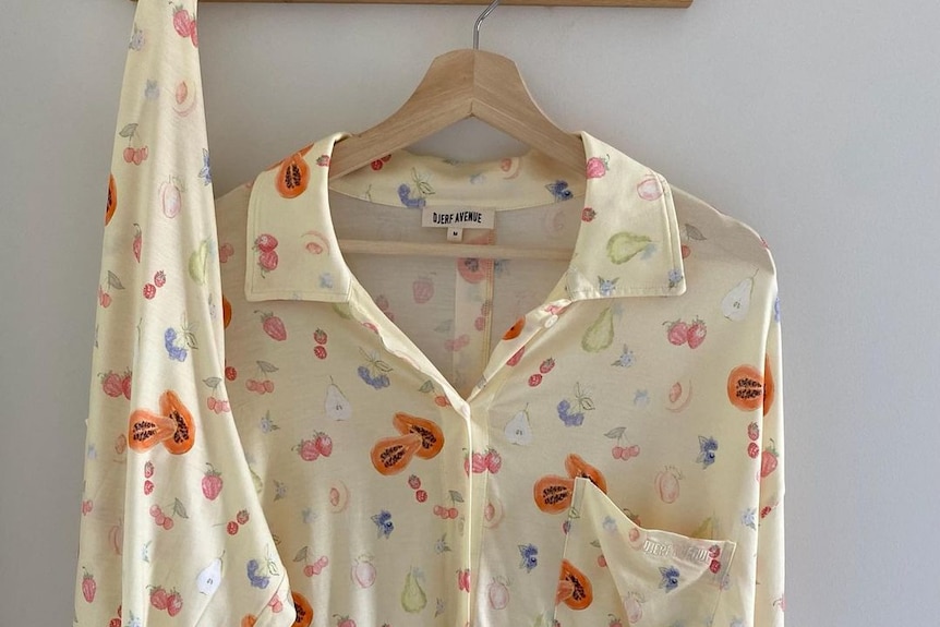 A pair of pyjamas with fruit print hang on a hanger