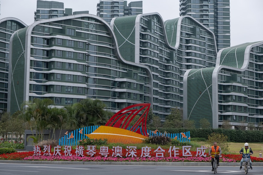 A tall building, some flower decorations and some Chinese boards. 