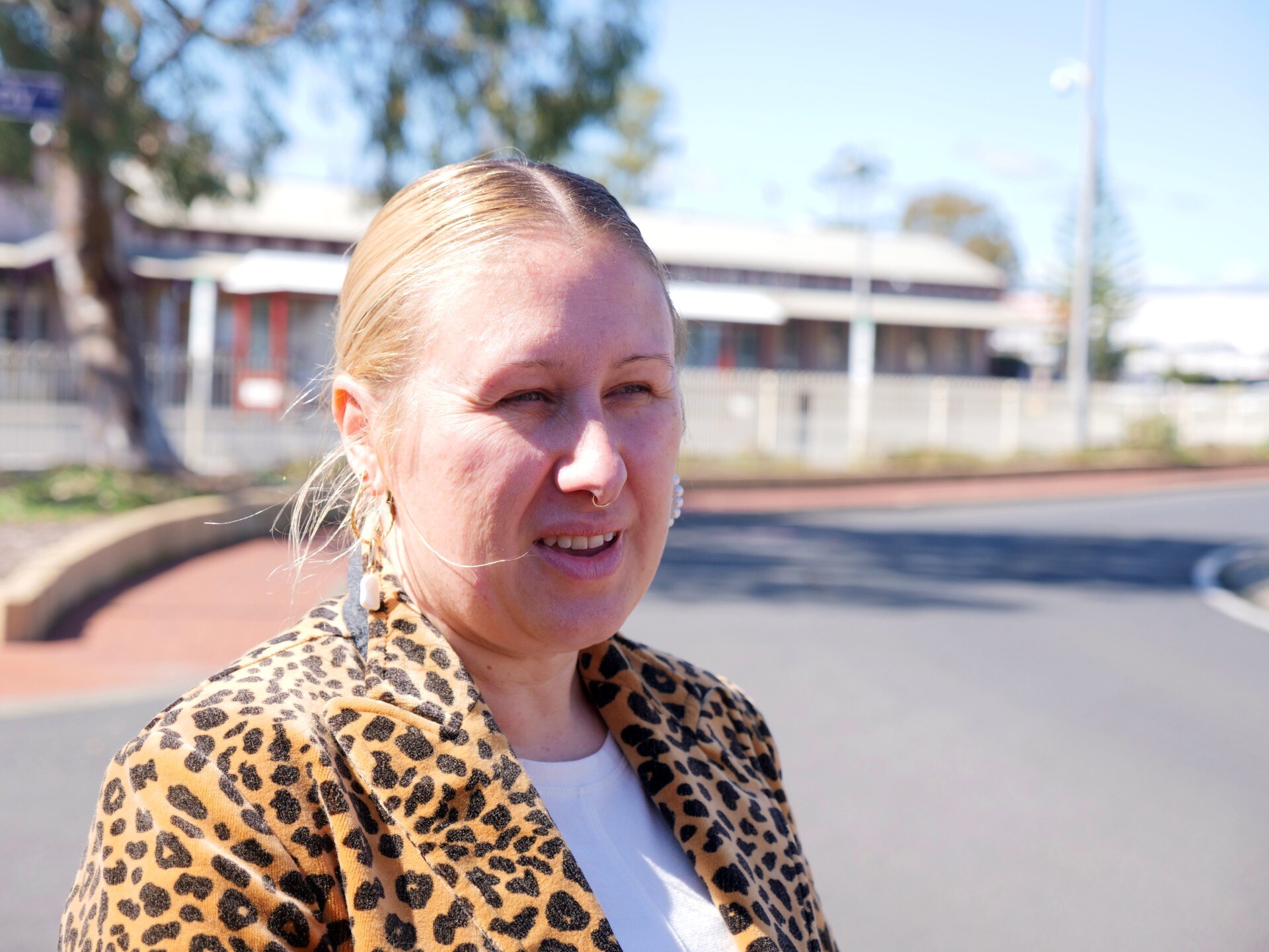 A woman stands talking in front of a bus station 