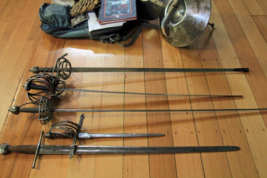 Four swords and a dagger on a wooden floor