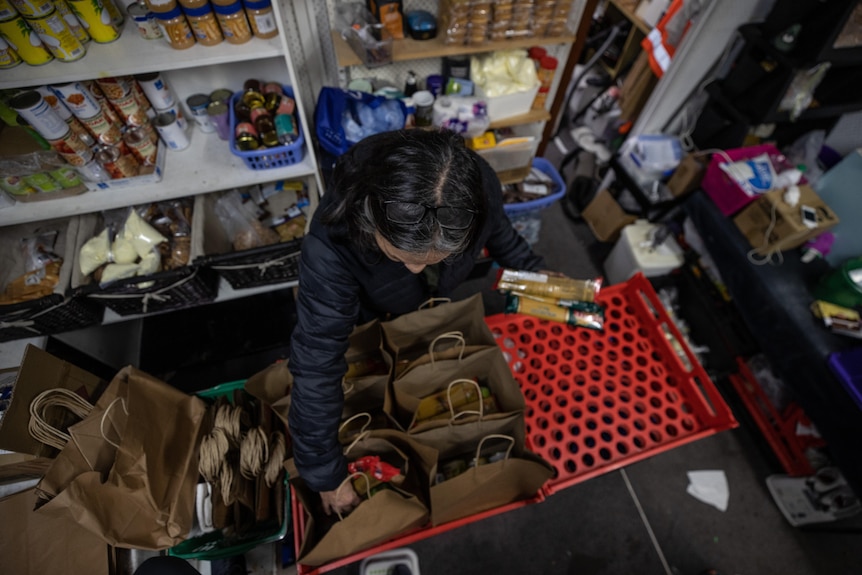 An aerial shot of the 2 x 1 metre space with Debbie placing spaghetti into brown paper bags. 