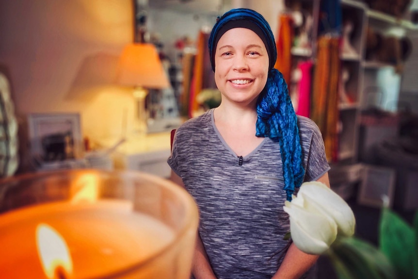 A woman wearing a turban-like head-wrap smiles at the camera.