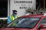 A health worker in PPE testing someone in a car outside the Crossroads Hotel.