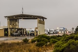 A wide shot showing a long queue of cars and trucks at the Eucla border checkpoint.