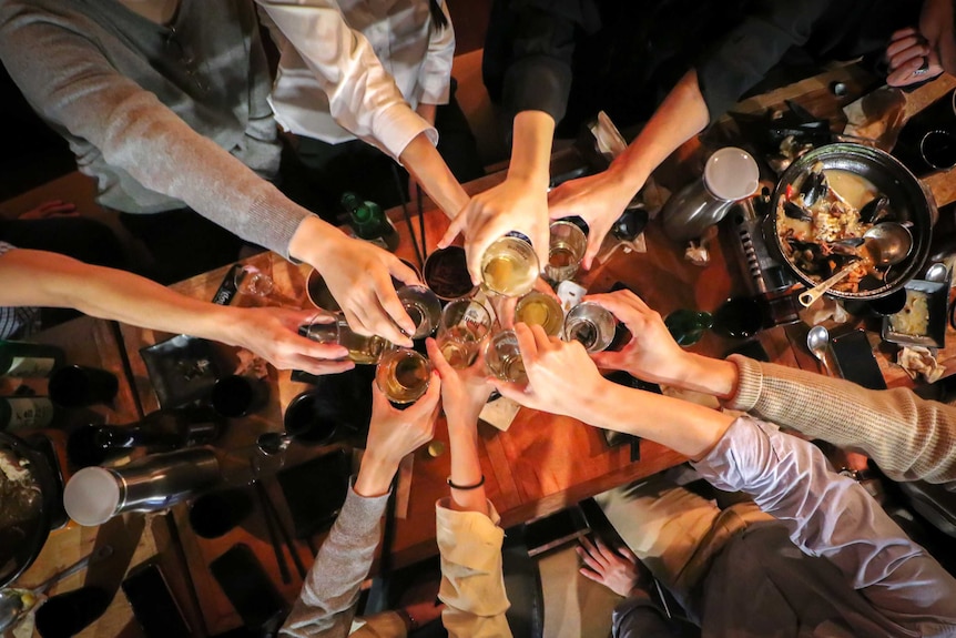 An overhead shot of group of people clinking their drinks together