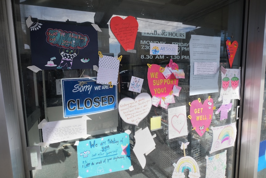 Paper love hearts taped to the front of a drycleaning business next to a shop closed sign.