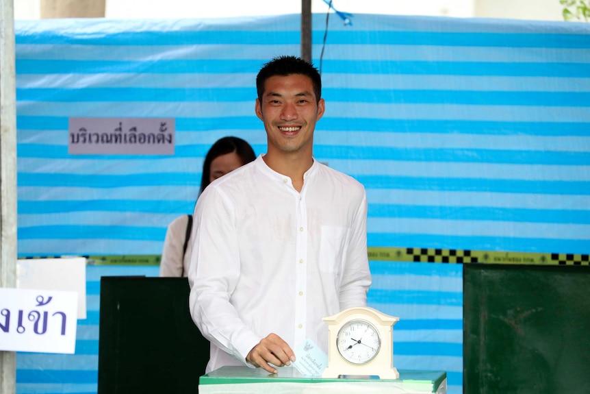 Thanathorn Juangroongruangkit, leader of Future Forward Party, smiles wearing a white shirt at a polling station.