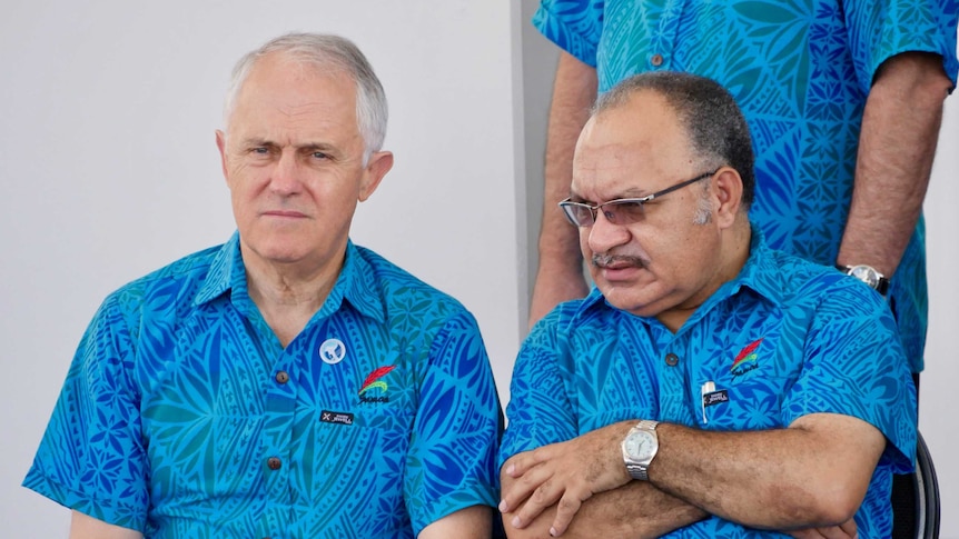 Malcolm Turnbull and Peter O'Neill sit side-by-side wearing the same blue, patterned shirts