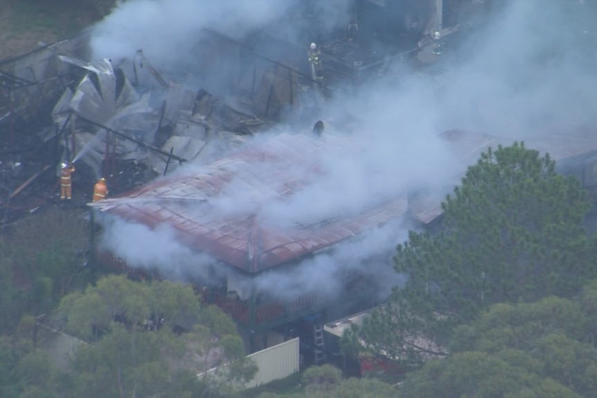 Firefighters work to extinguish a fire at a house on Russell Island in Queensland.