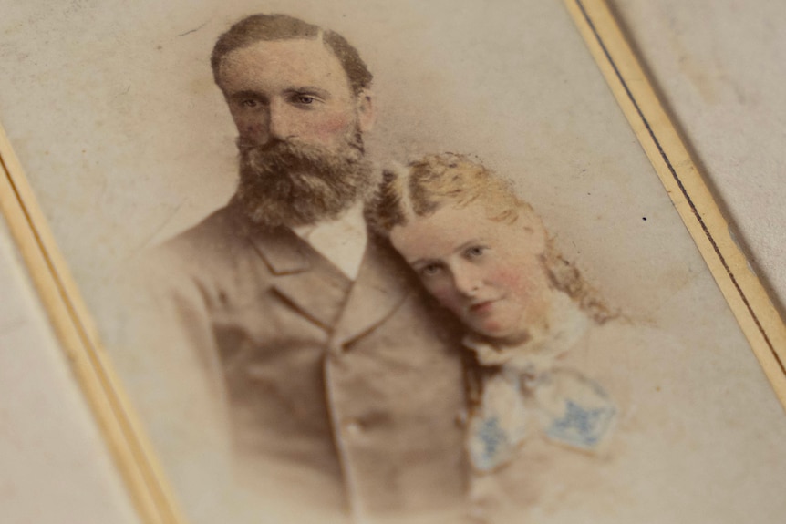 A young woman stands next to a bearded man and pose for a photo.
