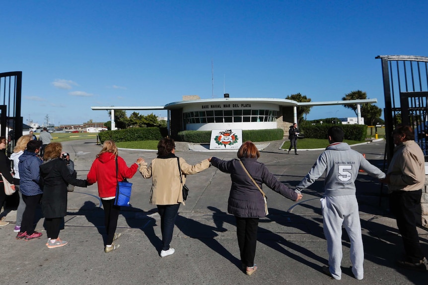 A group of people pray in support of the ARA San Juan's crew, linking hands near the gate of the Mar del Plata naval base.