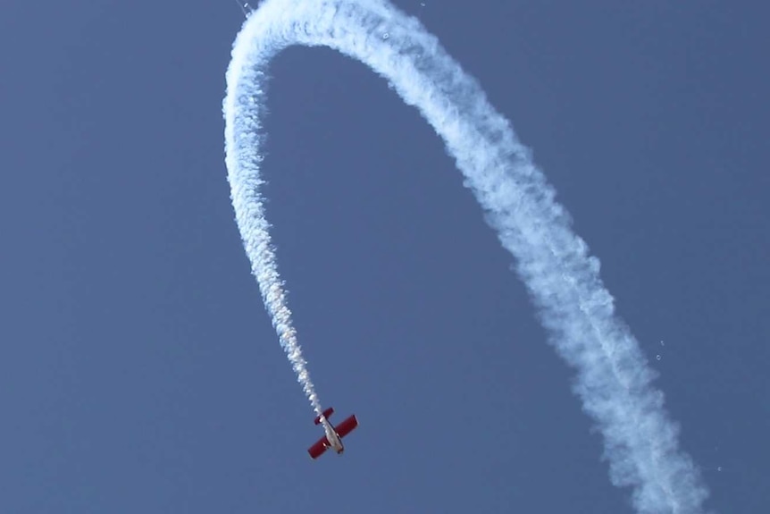 Plane in blue sky doing a loop with smoke tracing planes path