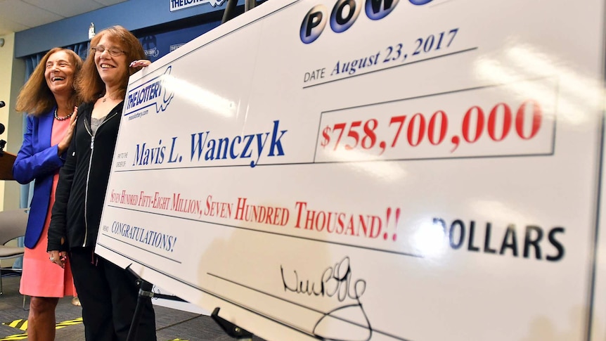 A woman stands next to a poster displaying her lottery winnings.