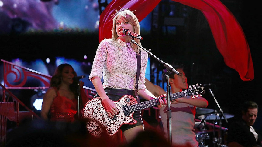 Blonde woman with guitar at microphone