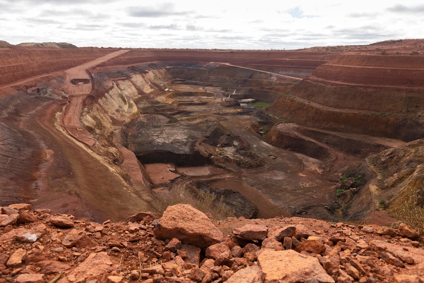 Massive hole in the ground with tiers of red dirt
