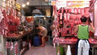 Men stand among meat in a wet market in China.