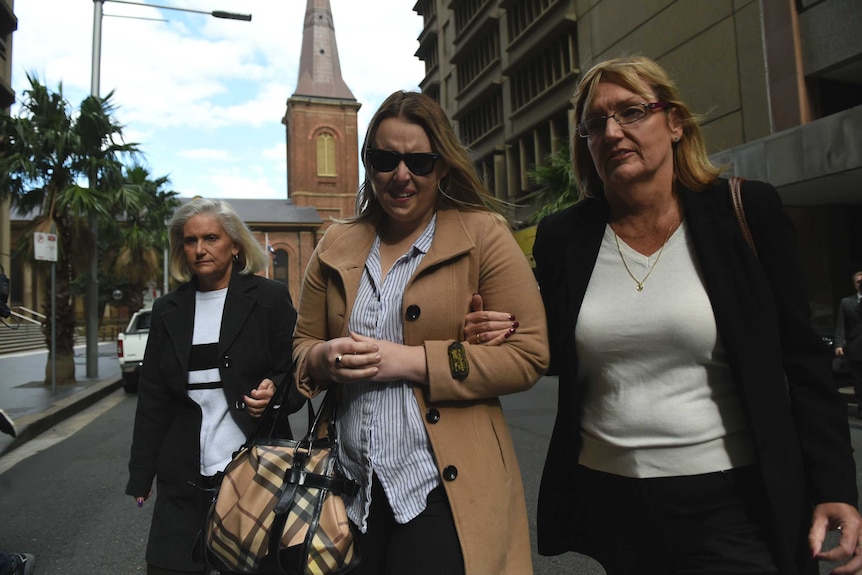 Jessica McNamara looking distressed, flanked by two women outside court.