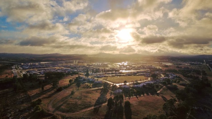 The sun begins to peek out over Canberra rooftops covered in snow.