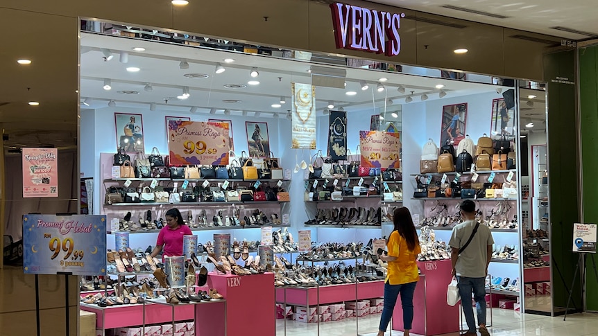 Customers stand near the entrance of a shoe store called Vern's in a modern shopping mall