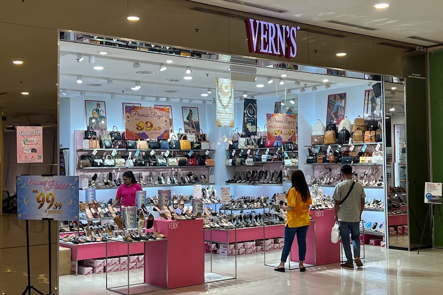 Customers stand near the entrance of a shoe store called Vern's in a modern shopping mall